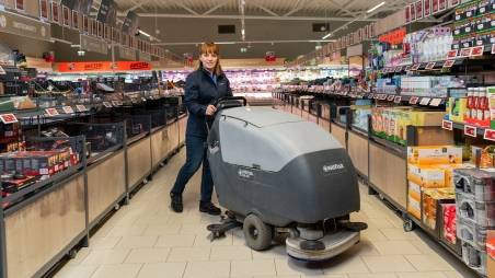 Veikala darbinieks veic telpu uzkopšanu ar specializētu aprīkojumu